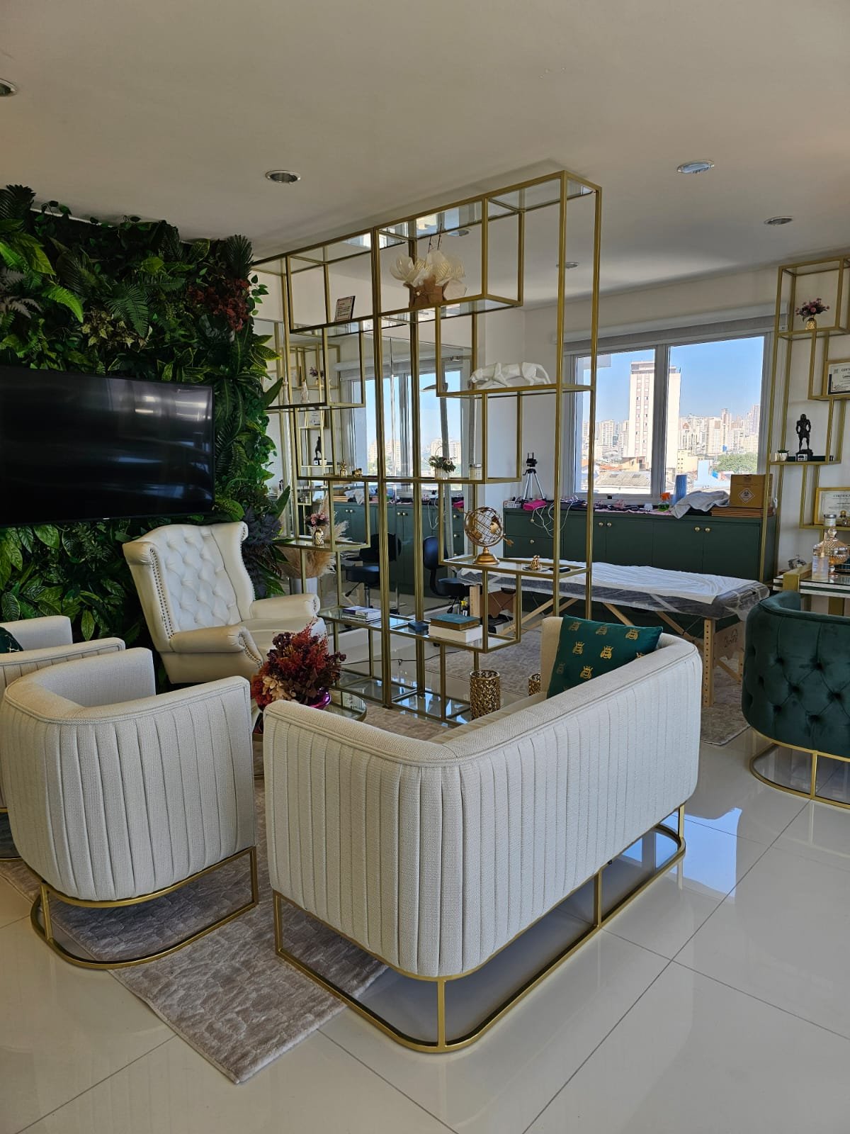 Poltronas e sofá em tons claros com detalhes dourados