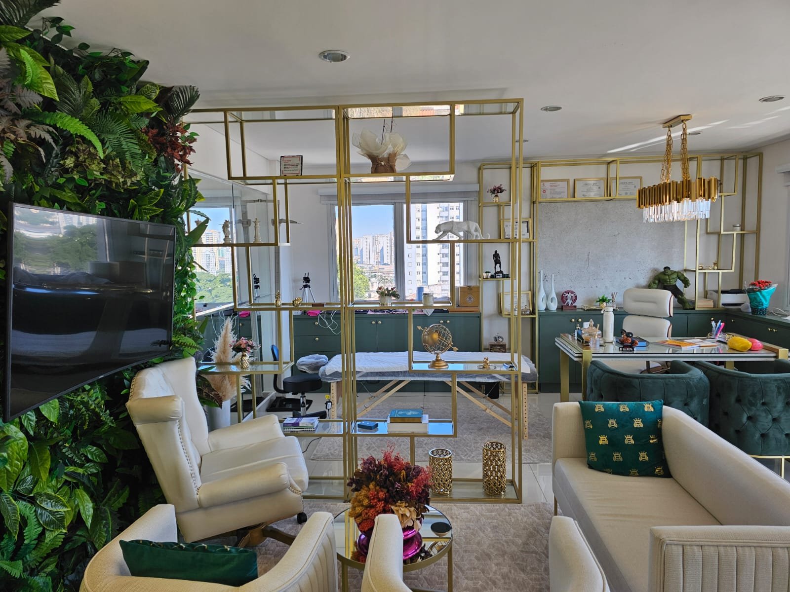 Sala de espera com poltronas claras, parede verde e estante dourada